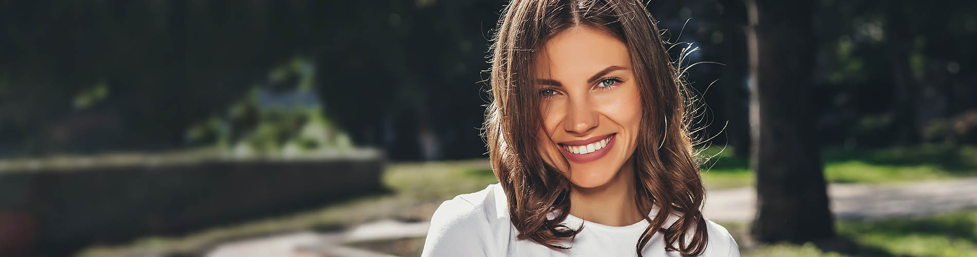 The image is a photograph of a woman with light skin, smiling at the camera. She appears to be in her late twenties or early thirties and has long hair. Her eyes are looking directly at the camera, and she is holding up her index finger near her mouth as if she s making a point or emphasizing something. The background is plain and light-colored, which suggests that this could be a stock photo used for various purposes such as advertising, personal branding, or lifestyle content.